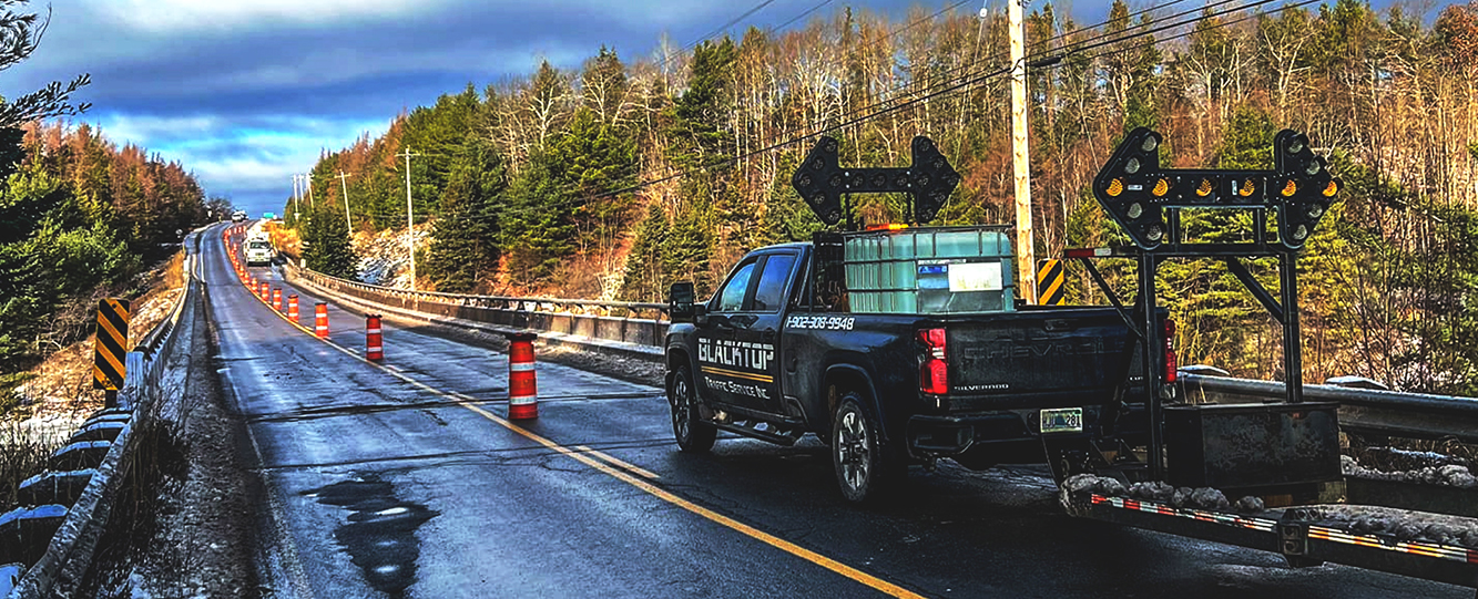Blacktop Traffic Service truck with arrow board and traffic delineators on Nova Scotia highway