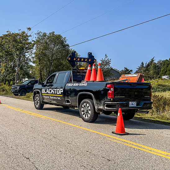Blacktop Traffic Service truck with arrow board and cones on road